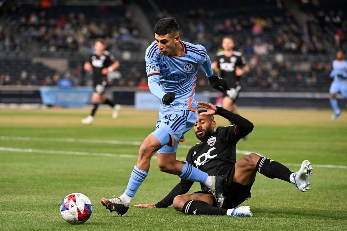 Mar 18, 2023; New York, New York, USA; New York City FC midfielder Santiago Rodriguez (10) jumps over a sliding D.C. United defender Ruan (2) during the first half at Yankee Stadium.