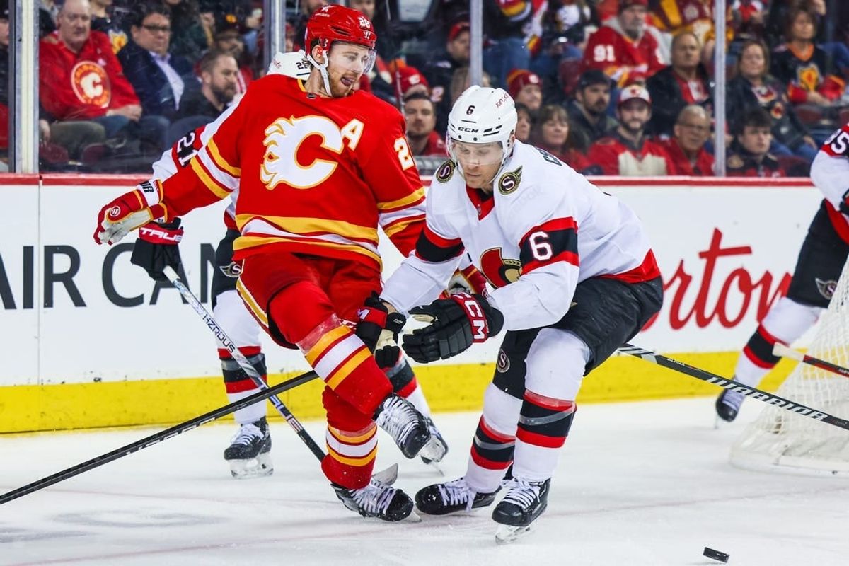 Jan 9, 2024; Calgary, Alberta, CAN; Calgary Flames center Elias Lindholm (28) passes the puck with his skate against Ottawa Senators defenseman Jakob Chychrun (6) during the second period at Scotiabank Saddledome.