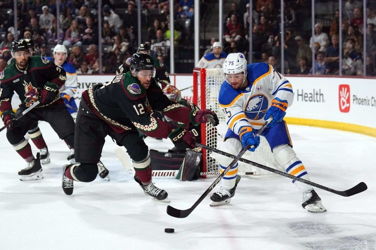 Dec 16, 2023; Tempe, Arizona, USA; Arizona Coyotes left wing Zach Sanford (12) checks Buffalo Sabres defenseman Connor Clifton (75) during the first period at Mullett Arena.