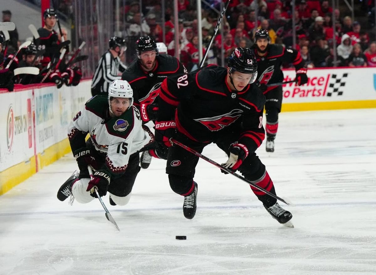 Jan 27, 2024; Raleigh, North Carolina, USA; Carolina Hurricanes center Jesperi Kotkaniemi (82) skates with the puck past Arizona Coyotes center Alexander Kerfoot (15) during the third period at PNC Arena.