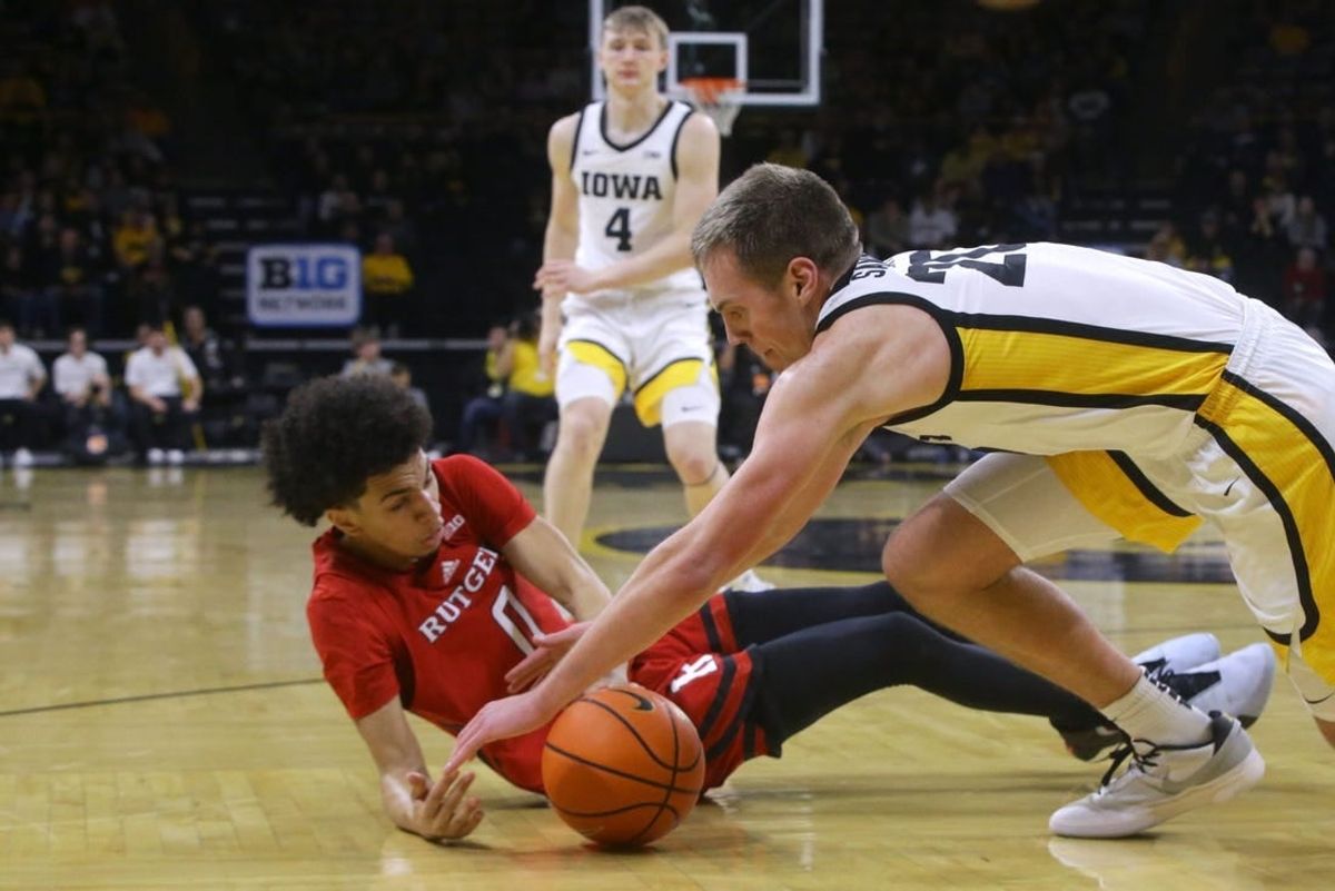 Iowa's Payton Sandfort (20) dives for a loose ball with Rutgers' Derek Simpson (0) Saturday, Jan. 6, 2024 at Carver-Hawkeye Arena in Iowa City, Iowa.