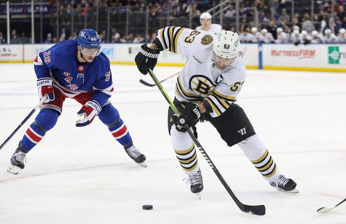Nov 25, 2023; New York, New York, USA; Boston Bruins left wing Brad Marchand (63) plays the puck in front of New York Rangers left wing Jimmy Vesey (26) during the third period at Madison Square Garden.