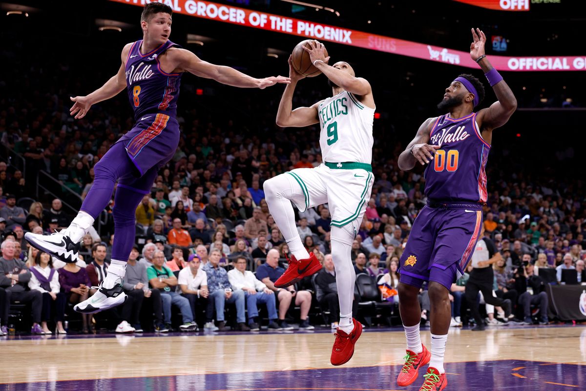 PHOENIX, ARIZONA - MARCH 09: Derrick White #9 of the Boston Celtics attempts a layup against Grayson Allen #8 and Royce O'Neale #00 of the Phoenix Suns during the first half at Footprint Center on March 09, 2024 in Phoenix, Arizona. NOTE TO USER: User expressly acknowledges and agrees that, by downloading and or using this photograph, User is consenting to the terms and conditions of the Getty Images License Agreement.  (Photo by Chris Coduto/Getty Images)