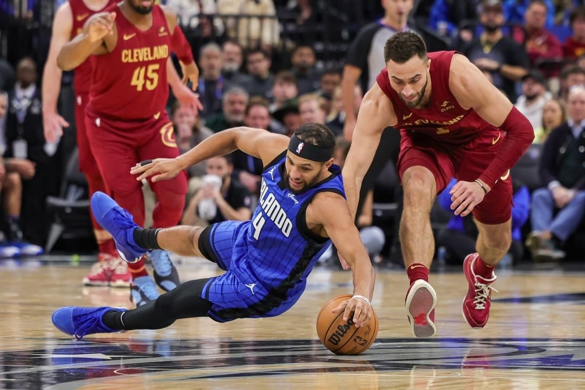 Dec 11, 2023; Orlando, Florida, USA; Orlando Magic guard Jalen Suggs (4) and Cleveland Cavaliers guard Max Strus (1) chase a loose ball during the second quarter at Amway Center.