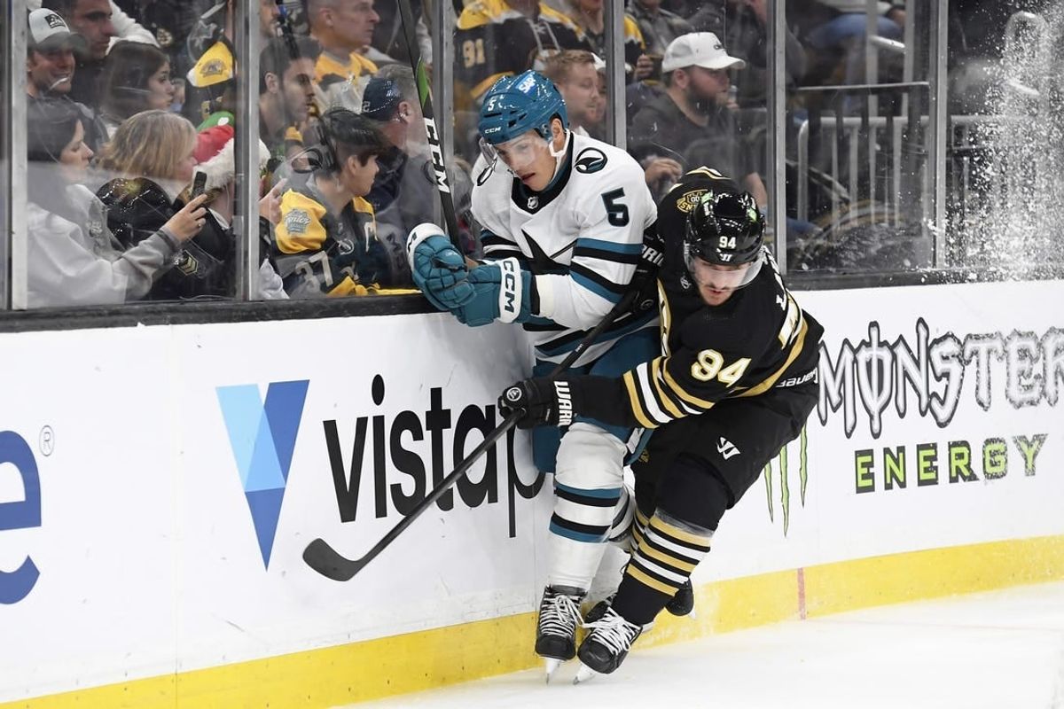 Nov 30, 2023; Boston, Massachusetts, USA; Boston Bruins center Jakub Lauko (94) checks San Jose Sharks defenseman Matt Benning (5) along the boards during the first period at TD Garden.