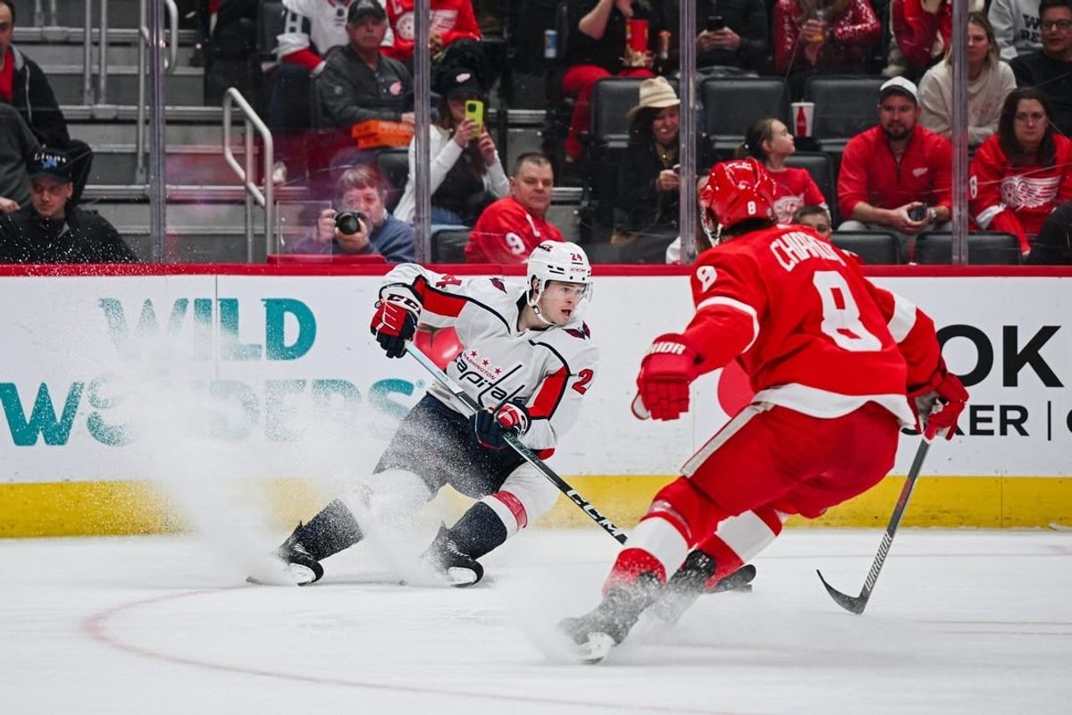 Feb 27, 2024; Detroit, Michigan, USA; Washington Capitals center Connor McMichael (24) brings the puck up ice against Detroit Red Wings defenseman Ben Chiarot (8) during the first period at Little Caesars Arena.