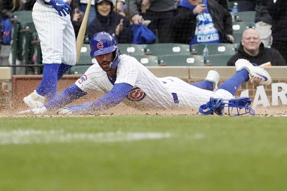 Apr 7, 2024; Chicago, Illinois, USA; Chicago Cubs shortstop Dansby Swanson (7) is safe at home plate against the Los Angeles Dodgers during the first inning at Wrigley Field.