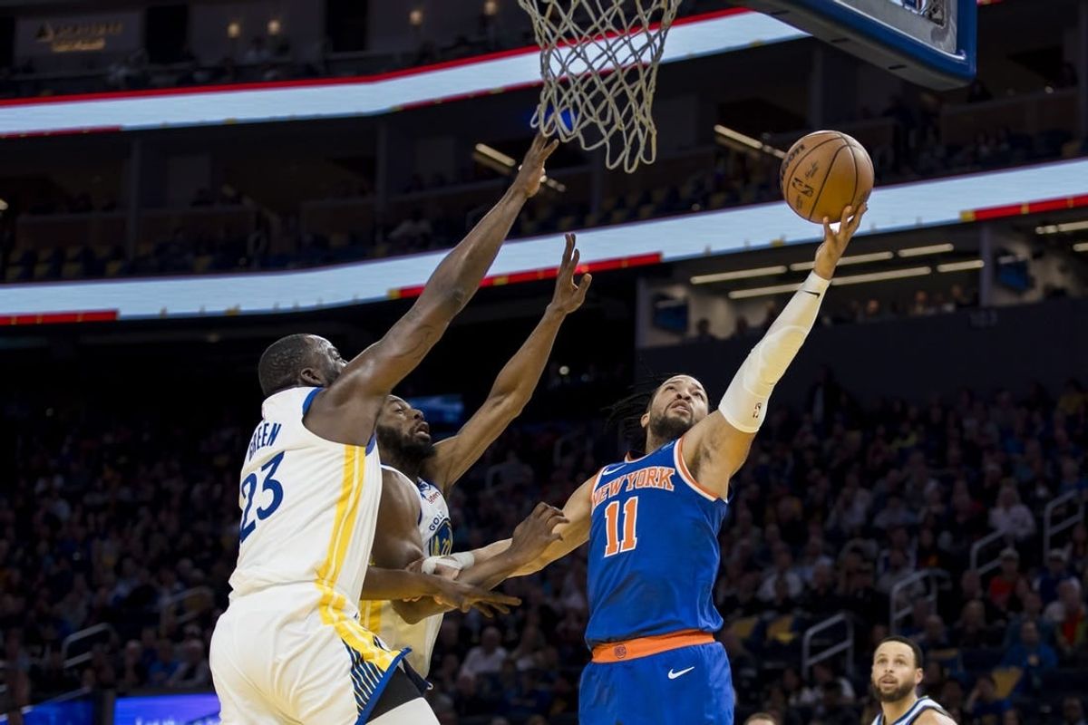 Mar 18, 2024; San Francisco, California, USA;  New York Knicks guard Jalen Brunson (11) shoots as Golden State Warriors center Draymond Green (23) and forward Andrew Wiggins (22) defend during the first half at Chase Center.