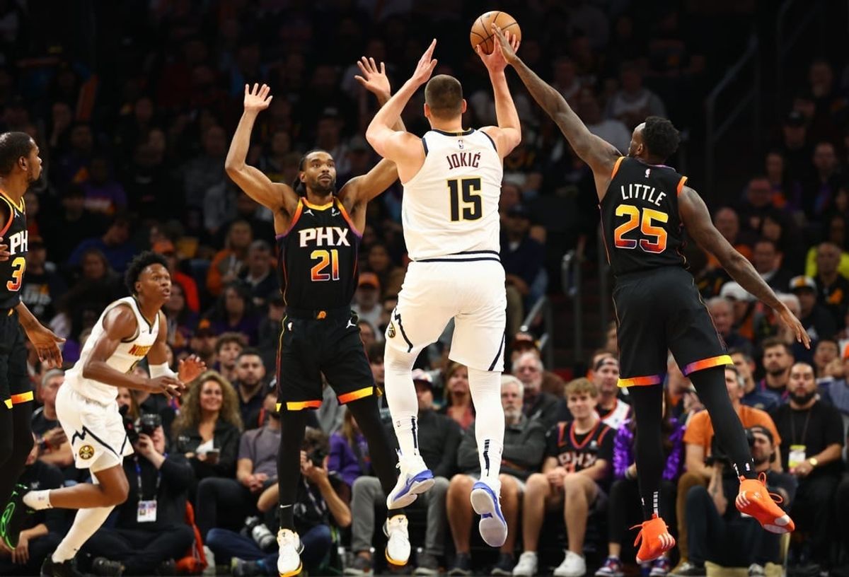 Dec 1, 2023; Phoenix, Arizona, USA; Denver Nuggets center Nikola Jokic (15) passes the ball against Phoenix Suns forward Keita Bates-Diop (21) and forward Nassir Little (25) in the first half at Footprint Center.