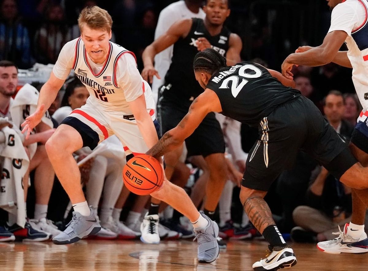 Mar 14, 2024; New York City, NY, USA;  Connecticut Huskies guard Cam Spencer (12) steals the ball from Xavier Musketeers guard Dayvion McKnight (20) during the first half at Madison Square Garden.