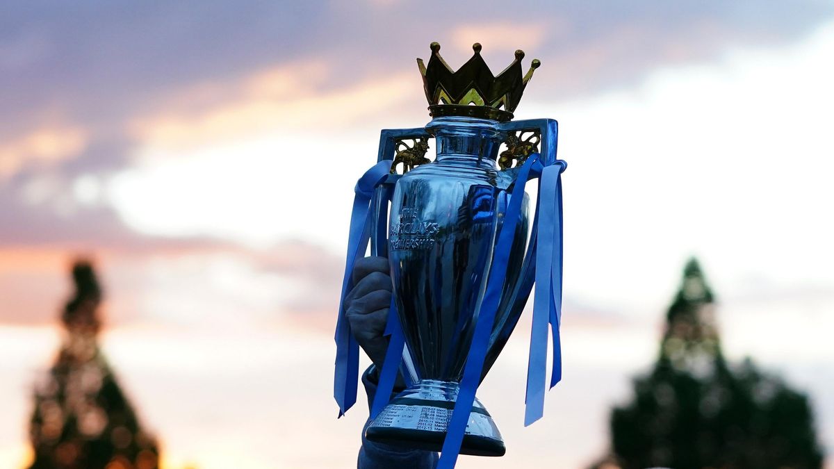 A Manchester City supporter holds up a replica of the English Premier League trophy as he celebrates outside the Etihad Stadium in Manchester, England,  after his team clinched the title. City took the title after crosstown rivals Manchester United lost at home to Leicester City.