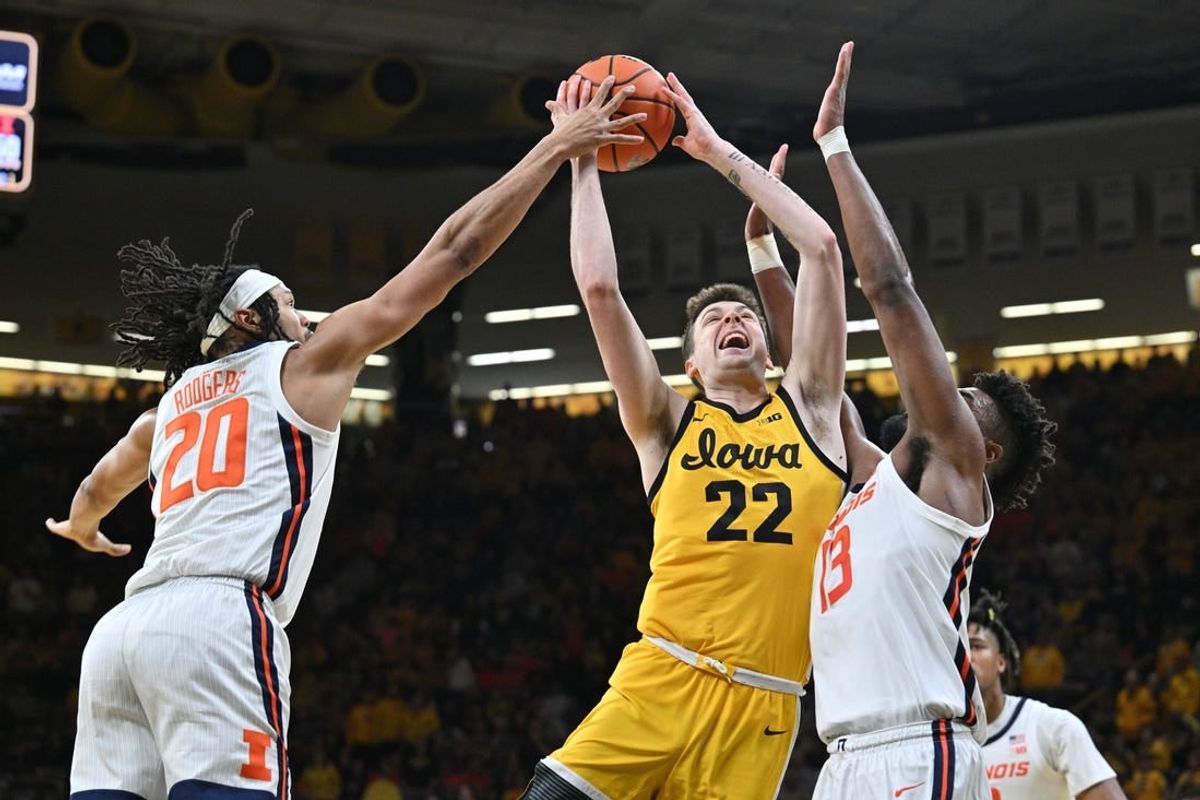 Mar 10, 2024; Iowa City, Iowa, USA; Iowa Hawkeyes forward Payton Sandfort (20) is defended by Illinois Fighting Illini forward Ty Rodgers (20) and forward Quincy Guerrier (13) during the second half at Carver-Hawkeye Arena.