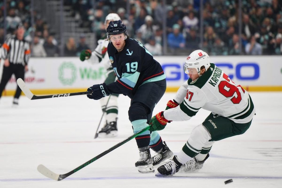 Dec 10, 2023; Seattle, Washington, USA; Seattle Kraken left wing Jared McCann (19) passes the puck past Minnesota Wild left wing Kirill Kaprizov (97) during the first period at Climate Pledge Arena.