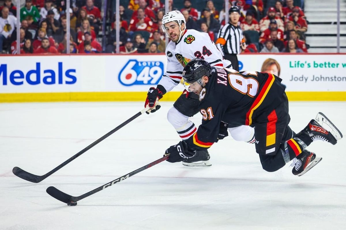 Jan 27, 2024; Calgary, Alberta, CAN; Calgary Flames center Nazem Kadri (91) controls the puck against Chicago Blackhawks defenseman Jaycob Megna (24) during the second period at Scotiabank Saddledome.