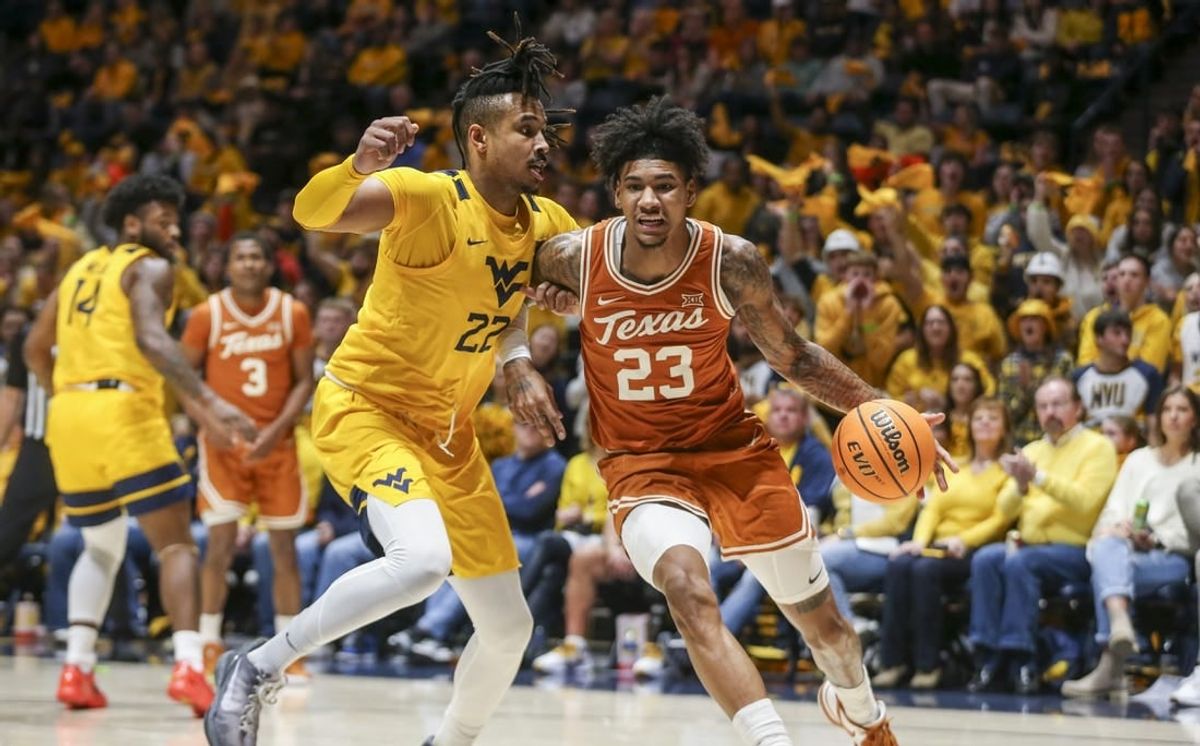 Jan 13, 2024; Morgantown, West Virginia, USA; Texas Longhorns forward Dillon Mitchell (23) drives baseline against West Virginia Mountaineers forward Josiah Harris (22) during the first half at WVU Coliseum.