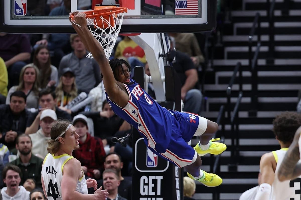 Feb 1, 2024; Salt Lake City, Utah, USA; Philadelphia 76ers guard Tyrese Maxey (0) hangs on the rim after a dunk against the Utah Jazz during the fourth quarter at Delta Center.