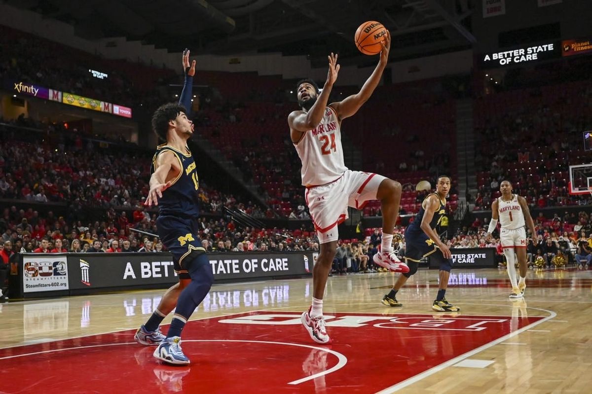 Jan 11, 2024; College Park, Maryland, USA;  Maryland Terrapins forward Donta Scott (24) shoots a sky hook over Michigan Wolverines forward Olivier Nkamhoua (13) during the second half at Xfinity Center.