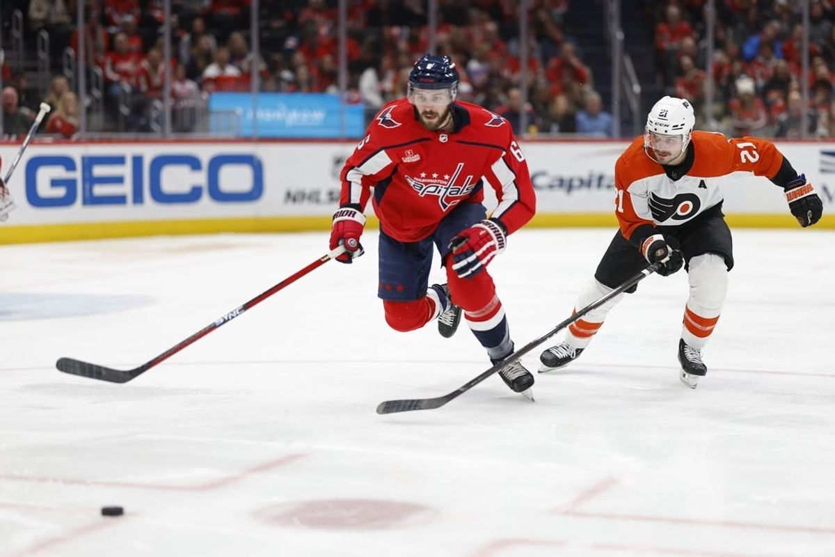 Mar 1, 2024; Washington, District of Columbia, USA; Washington Capitals defenseman Joel Edmundson (6) and Philadelphia Flyers center Scott Laughton (21) chase the puck in the second period at Capital One Arena.