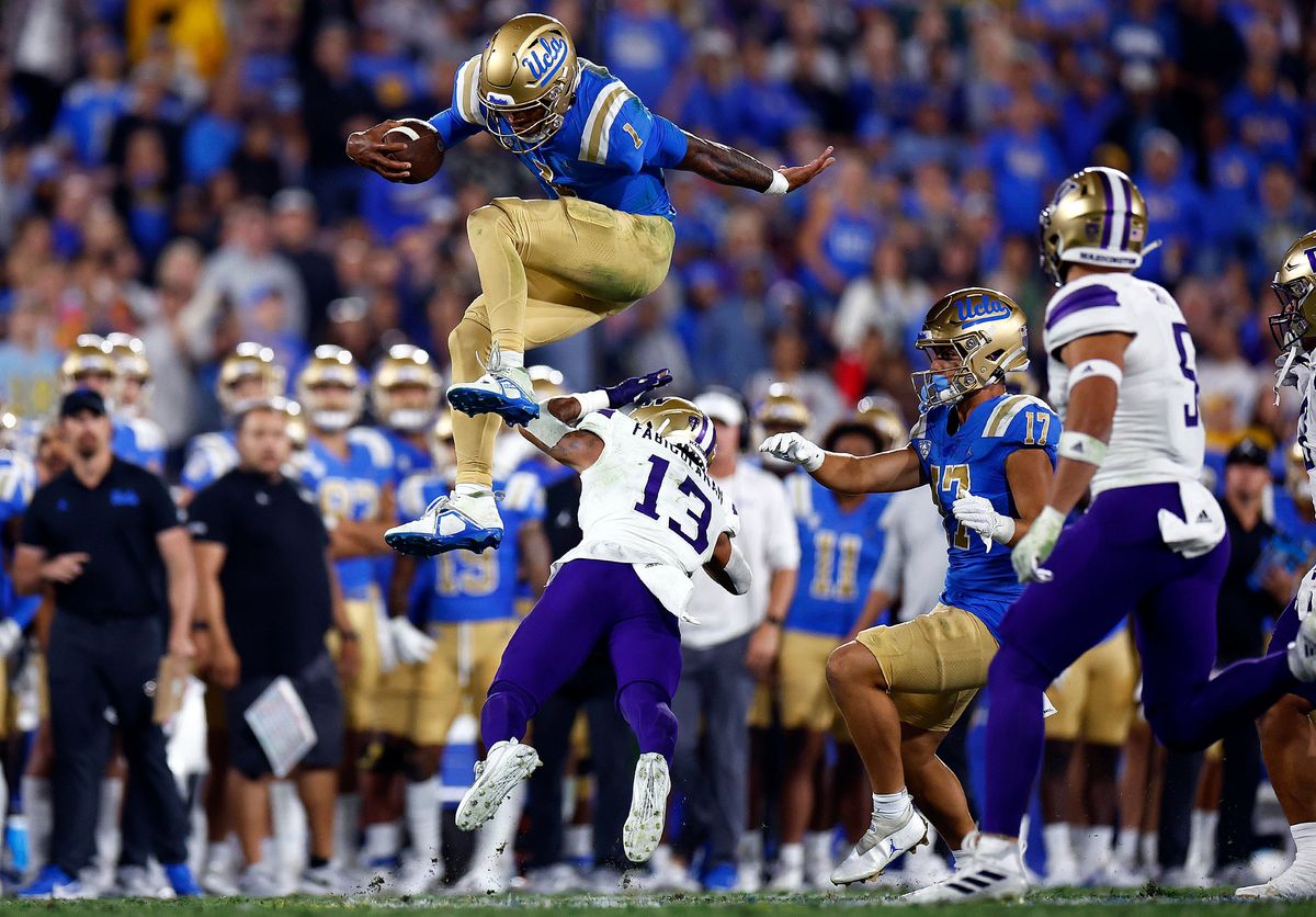 Dorian Thompson-Robinson of the UCLA Bruins jumps over Kamren Fabiculanan of the Washington Huskies in the second quarter at Rose Bowl Stadium on Sept. 30, 2022 in Pasadena, California.