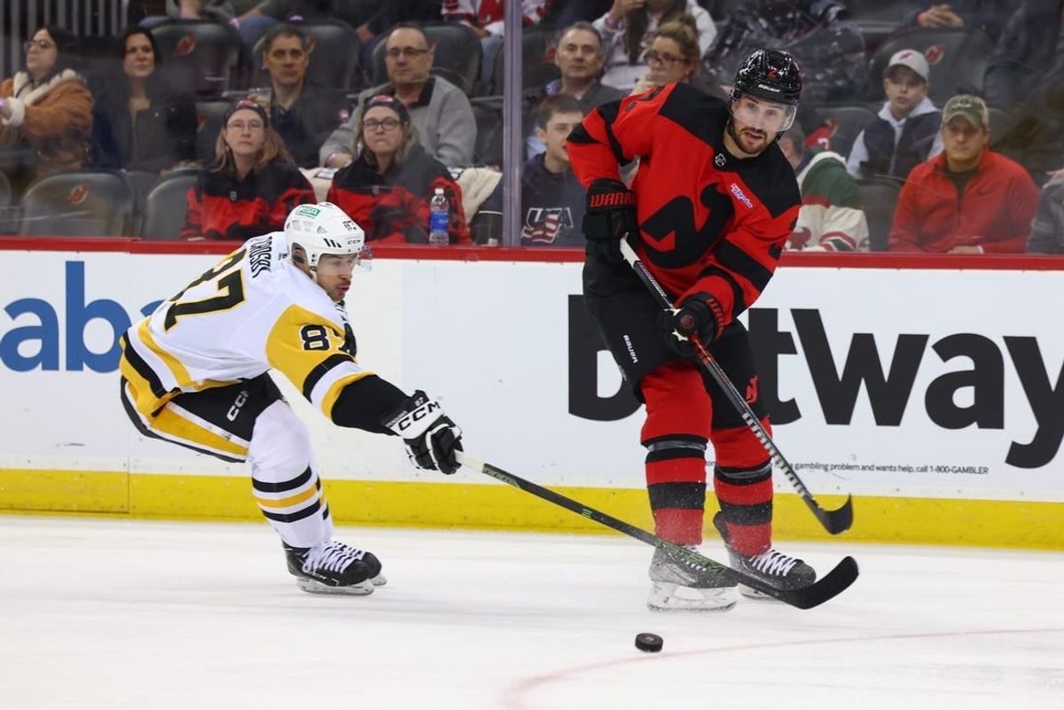 Mar 19, 2024; Newark, New Jersey, USA; New Jersey Devils defenseman Brendan Smith (2) passes the puck while being defended by Pittsburgh Penguins center Sidney Crosby (87) during the first period at Prudential Center.