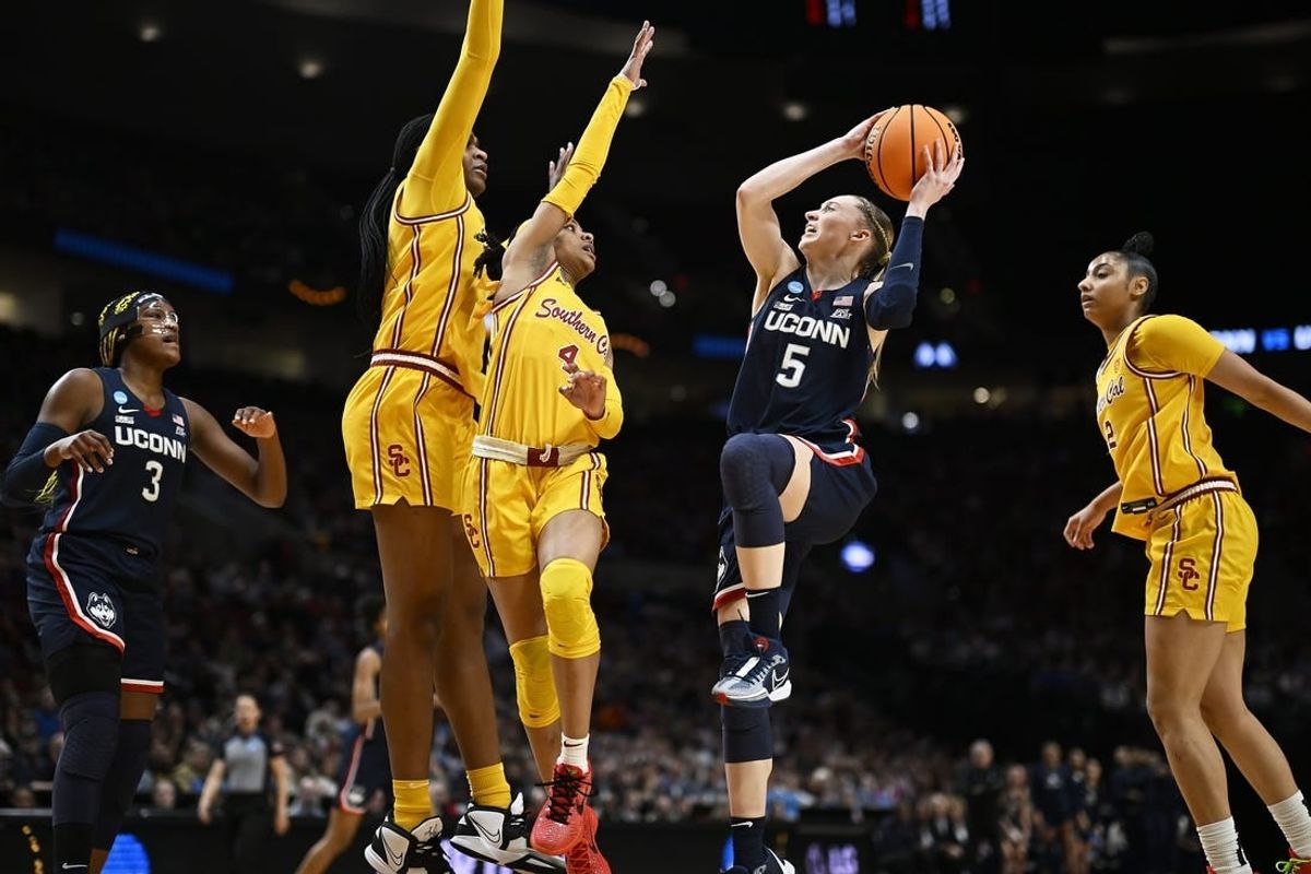 Apr 1, 2024; Portland, OR, USA; UConn Huskies guard Paige Bueckers (5) drives to the basket during the first half against USC Trojans guard Kayla Williams (4) and center Clarice Akunwafo (34)in the finals of the Portland Regional of the NCAA Tournament at the Moda Center.