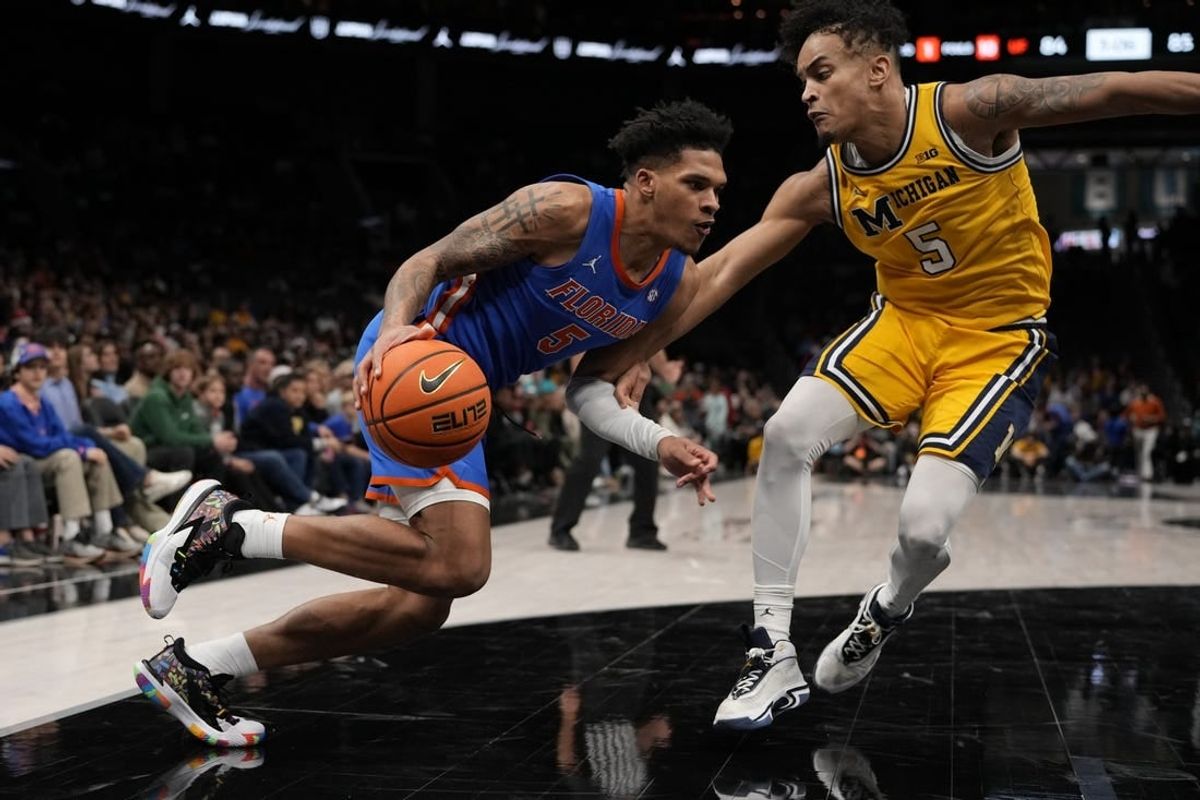 Dec 19, 2023; Charlotte, North Carolina, USA; Florida Gators guard Will Richard (5) drives to the basket against Michigan Wolverines forward Terrance Williams II (5) during the first overtime period at Spectrum Center.