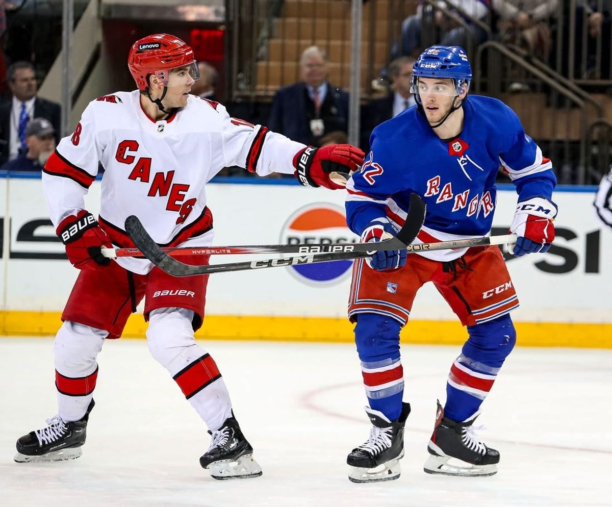 Jan 2, 2024; New York, New York, USA; Carolina Hurricanes center Jack Drury (18) and New York Rangers center Jonny Brodzinski (22) battle for position during the second period at Madison Square Garden.
