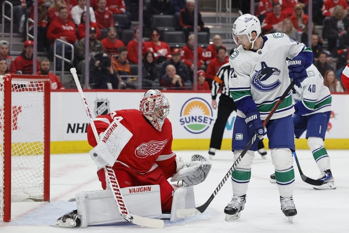 Feb 10, 2024; Detroit, Michigan, USA;  Detroit Red Wings goaltender Alex Lyon (34) makes a save in front of Vancouver Canucks center Elias Lindholm (23) in the first period at Little Caesars Arena.