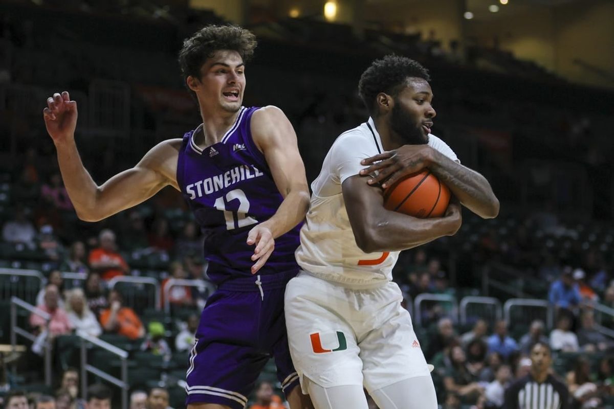 Dec 21, 2023; Coral Gables, Florida, USA; Miami Hurricanes guard Wooga Poplar (5) grabs a rebound against Stonehill Skyhawks guard Thatcher Stone (12) during the first half at Watsco Center.