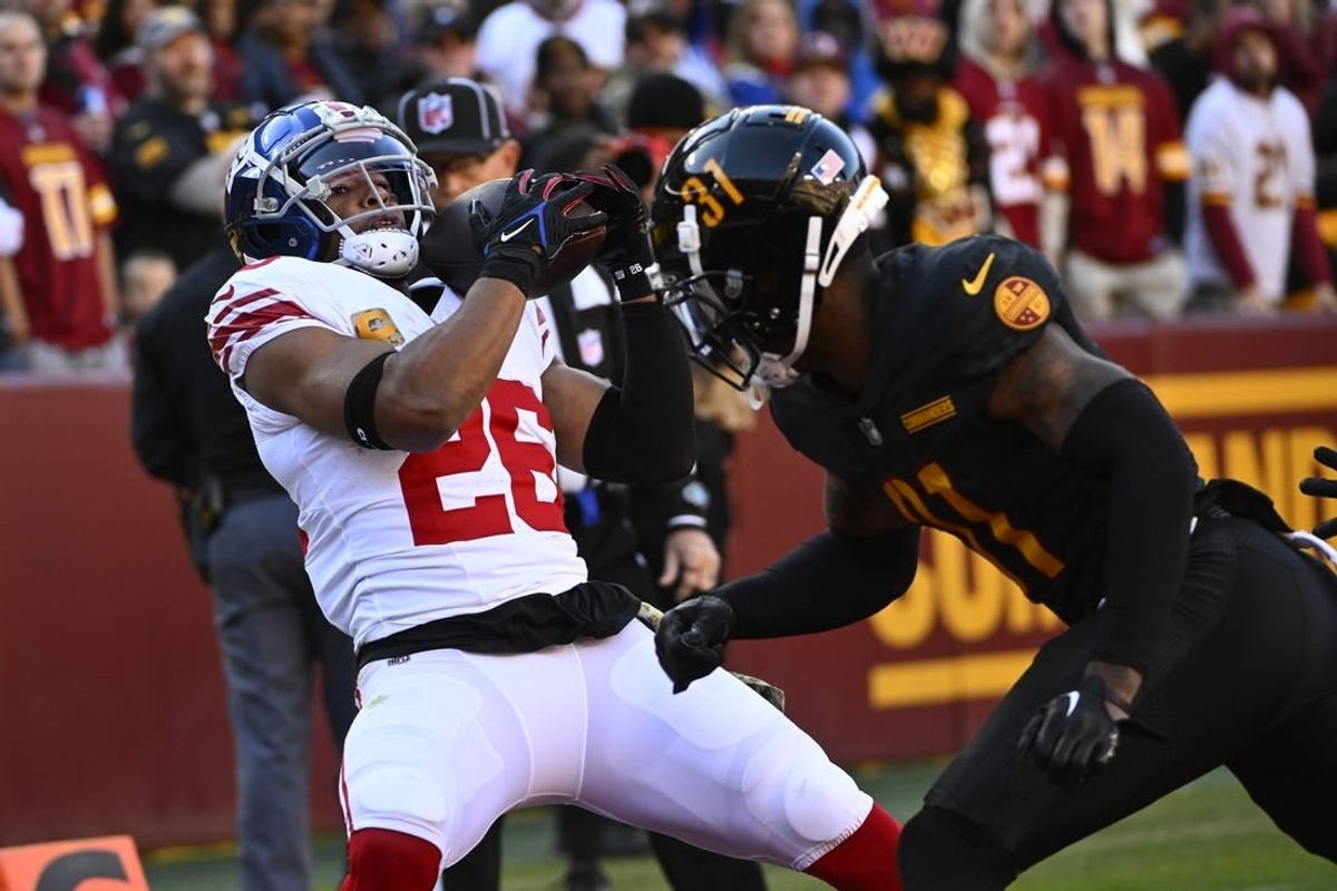 Nov 19, 2023; Landover, Maryland, USA; New York Giants running back Saquon Barkley (26) catches a touchdown  past Washington Commanders safety Kamren Curl (31) during the first half at FedExField.