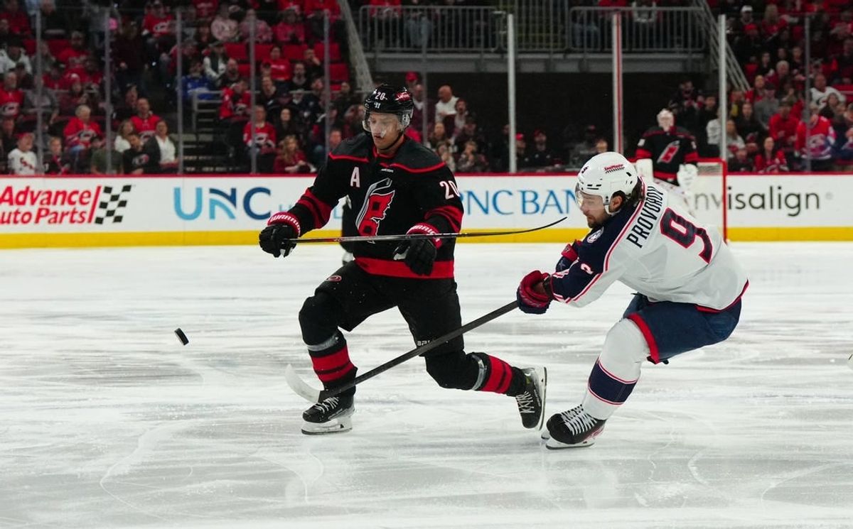 Apr 7, 2024; Raleigh, North Carolina, USA;  Columbus Blue Jackets defenseman Ivan Provorov (9) clears the puck away from Carolina Hurricanes center Sebastian Aho (20) during the first period at PNC Arena.