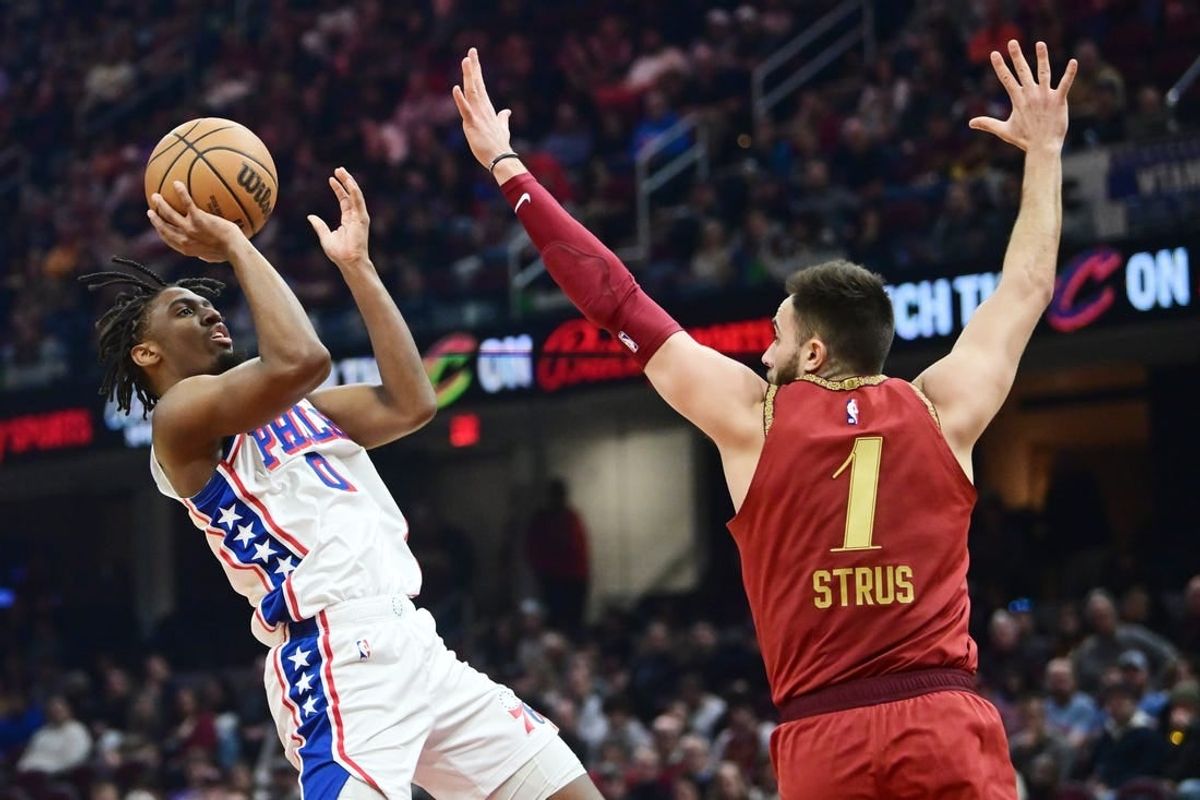 Feb 12, 2024; Cleveland, Ohio, USA; Philadelphia 76ers guard Tyrese Maxey (0) shoots over the defense of  Cleveland Cavaliers guard Max Strus (1) during the first half at Rocket Mortgage FieldHouse.