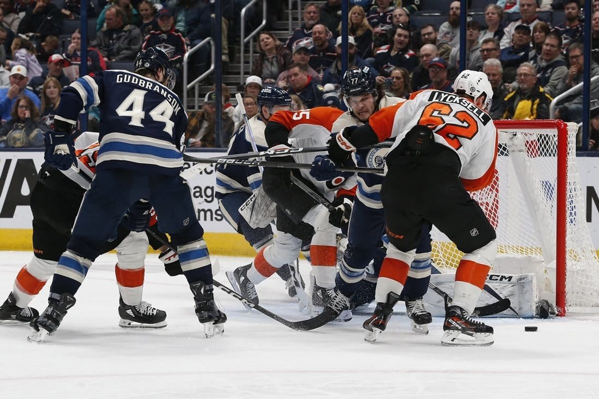 Apr 6, 2024; Columbus, Ohio, USA; Philadelphia Flyers right wing Olle Lycksell (62) reaches for the loose puck as Columbus Blue Jackets defenseman Nick Blankenburg (77)  defends during the second period at Nationwide Arena.