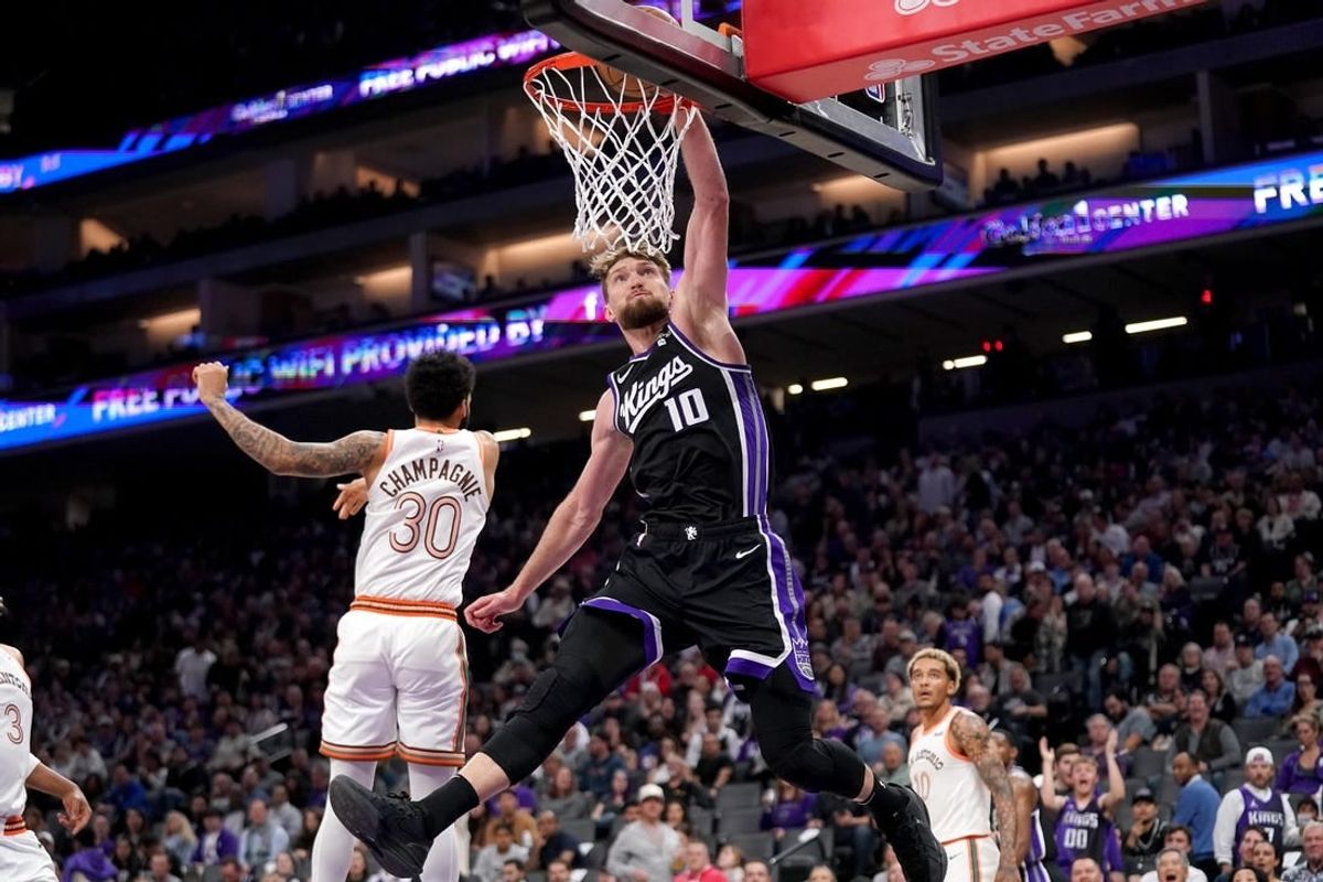 Mar 7, 2024; Sacramento, California, USA; Sacramento Kings forward Domantas Sabonis (10) dunks the ball in front of San Antonio Spurs forward Julian Champagnie (30) in the second quarter at the Golden 1 Center.