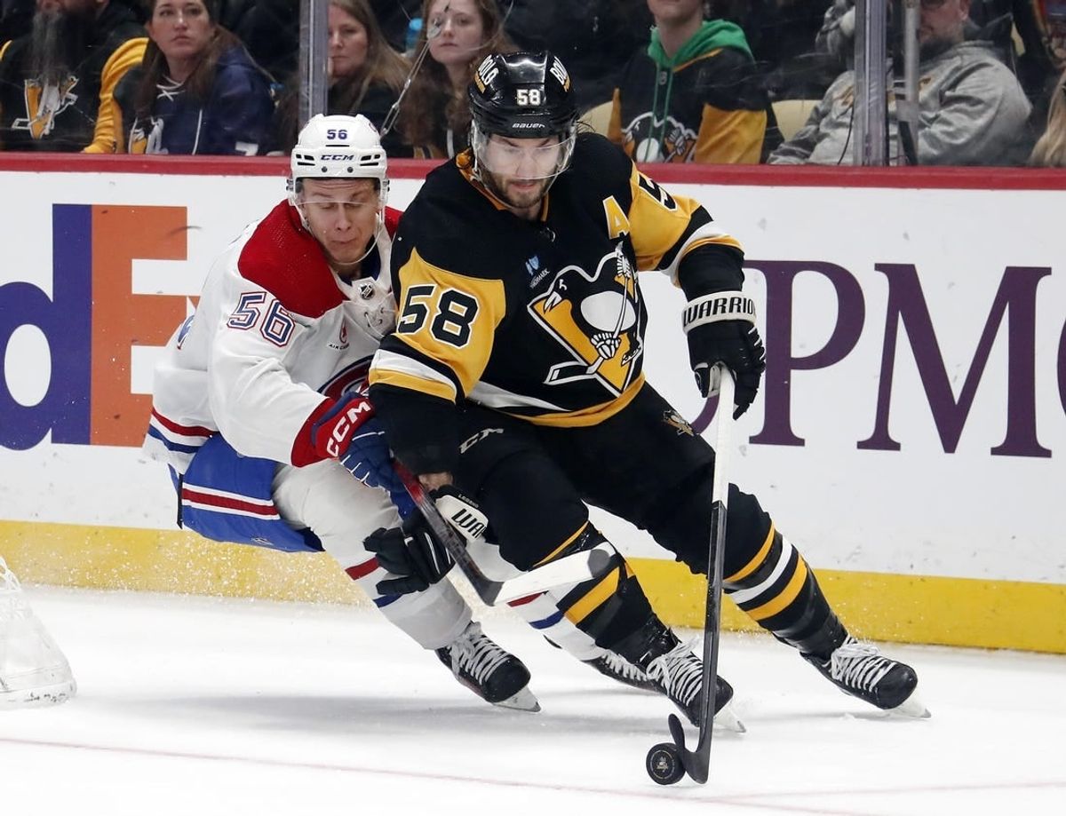 Jan 27, 2024; Pittsburgh, Pennsylvania, USA;  Pittsburgh Penguins defenseman Kris Letang (58) moves the puck ahead of Montreal Canadiens right wing Jesse Ylonen (56) during the second period  at PPG Paints Arena.