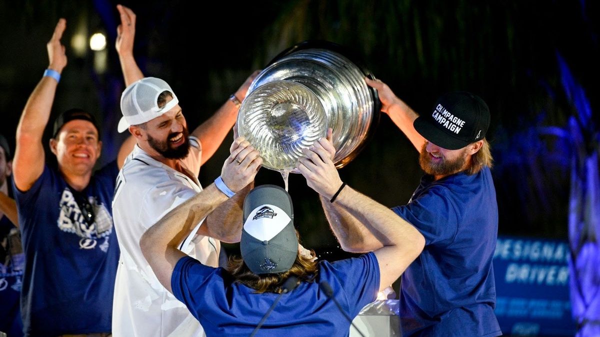 Alex Killorn and Steven Stamkos pour beer from the Stanley Cup into the mouth of Victor Hedman of the Tampa Bay Lightning during the 2020 Stanley Cup Champion rally in Tampa.