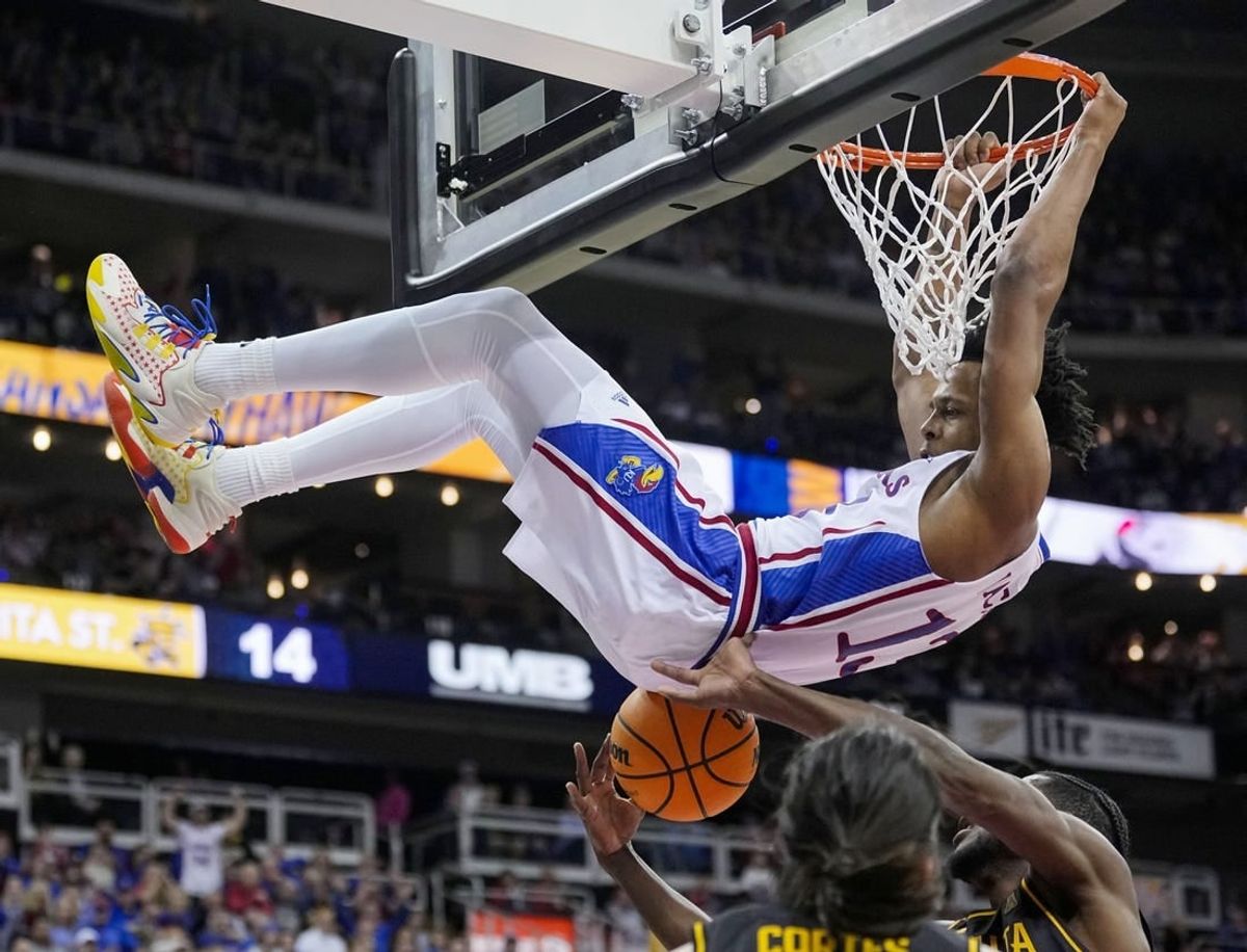 Dec 30, 2023; Kansas City, Missouri, USA; Kansas Jayhawks guard Elmarko Jackson (13) dunks against Wichita State Shockers center Quincy Ballard (15) and guard Bijan Cortes (55) during the first half at T-Mobile Center.