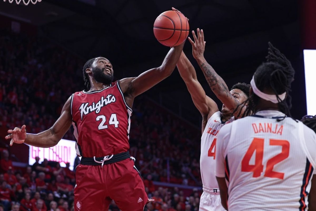 Dec 2, 2023; Piscataway, New Jersey, USA; Rutgers Scarlet Knights guard Austin Williams (24) rebounds against Illinois Fighting Illini guard Justin Harmon (4) and  forward Dain Dainja (42) during the first half at Jersey Mike's Arena.