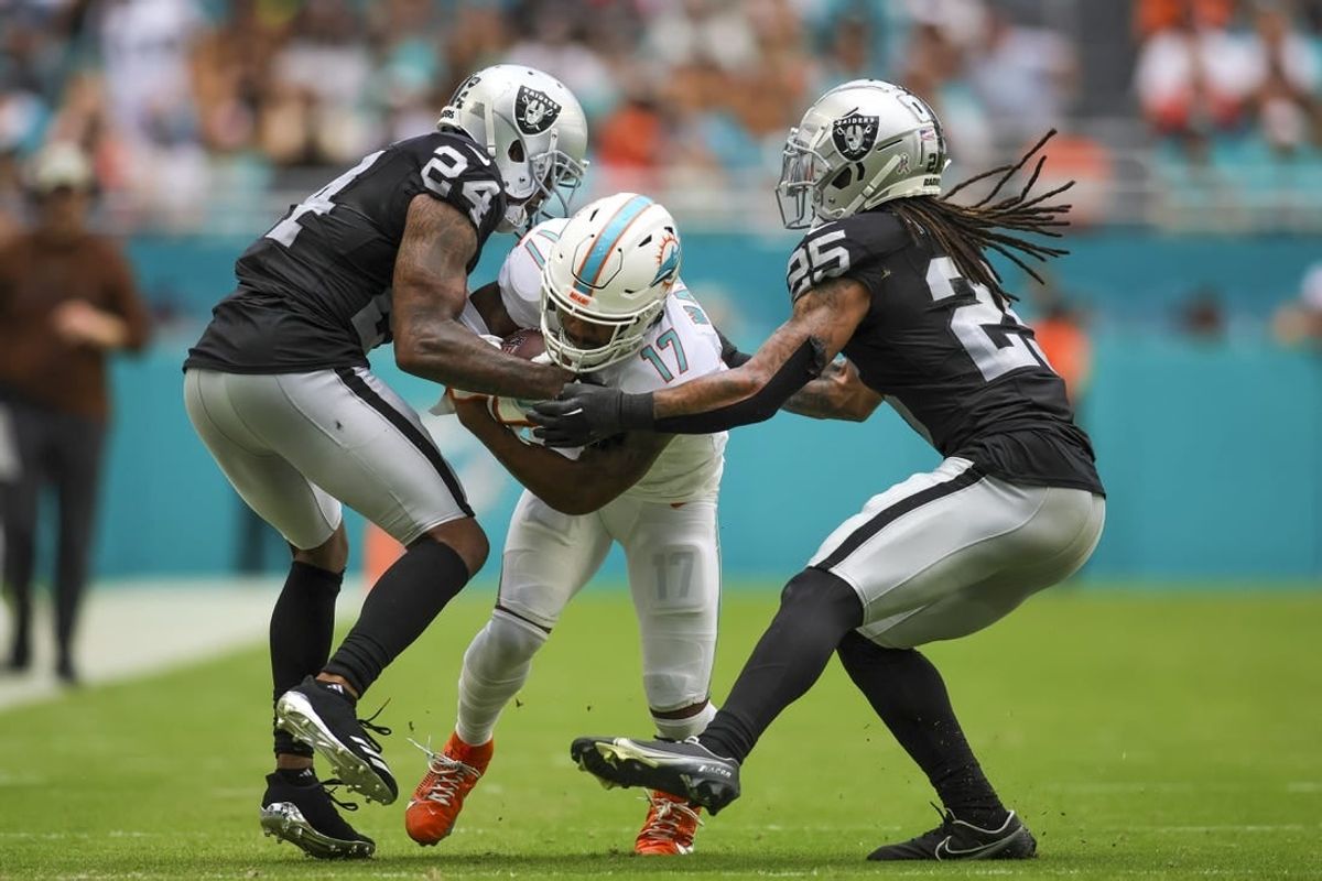 Nov 19, 2023; Miami Gardens, Florida, USA; Miami Dolphins wide receiver Jaylen Waddle (17) runs with the football as Las Vegas Raiders cornerback Marcus Peters (24) and safety Tre'von Moehrig (25) attempt to him during the second quarter at Hard Rock Stadium.