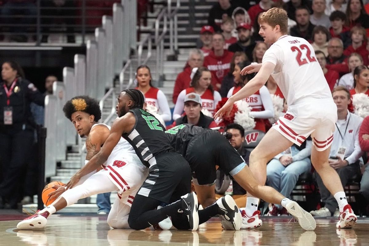 Dec 22, 2023; Madison, Wisconsin, USA; Wisconsin Badgers guard Chucky Hepburn (23) reaches a loose ball before Chicago State Cougars guard Brent Davis (12) as Chicago State Cougars forward Noble Crawford (15) and Wisconsin Badgers forward Steven Crowl (22) look on during the first half at the Kohl Center.