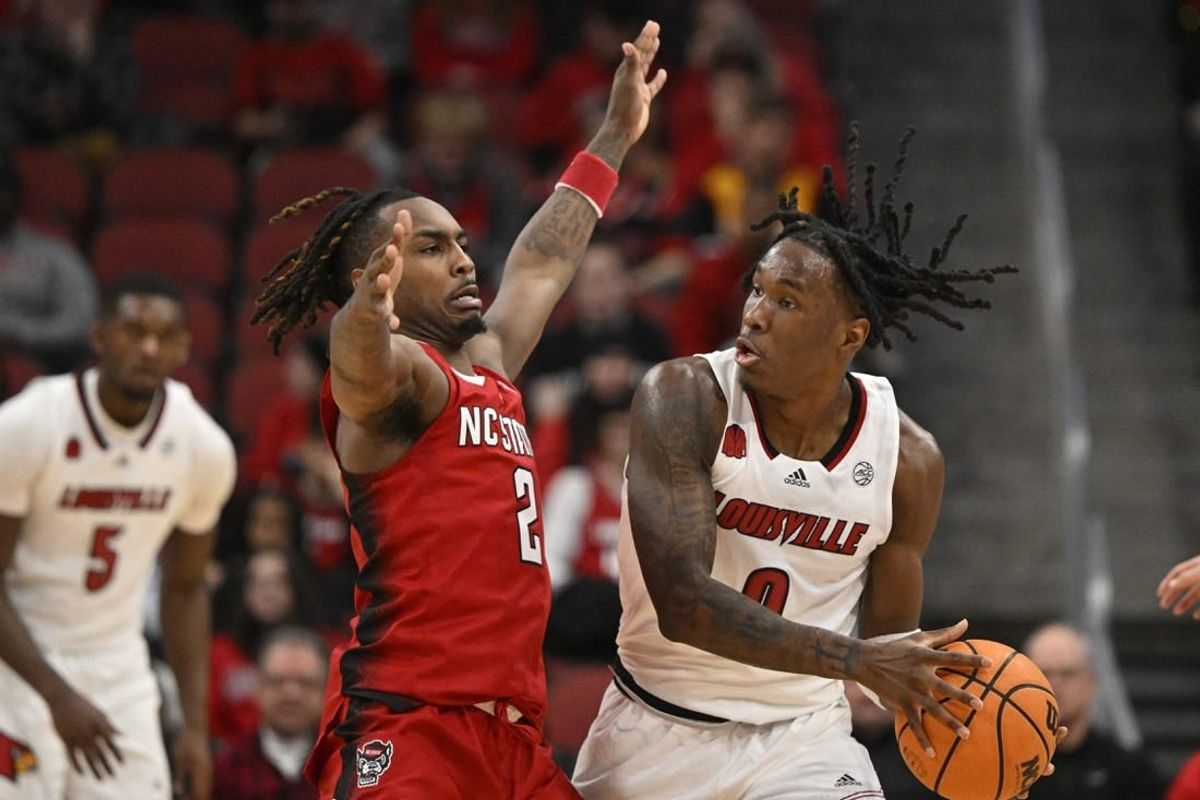 Jan 13, 2024; Louisville, Kentucky, USA;  Louisville Cardinals guard Mike James (0) controls the ball against North Carolina State Wolfpack guard Kam Woods (2) during the first half at KFC Yum! Center.