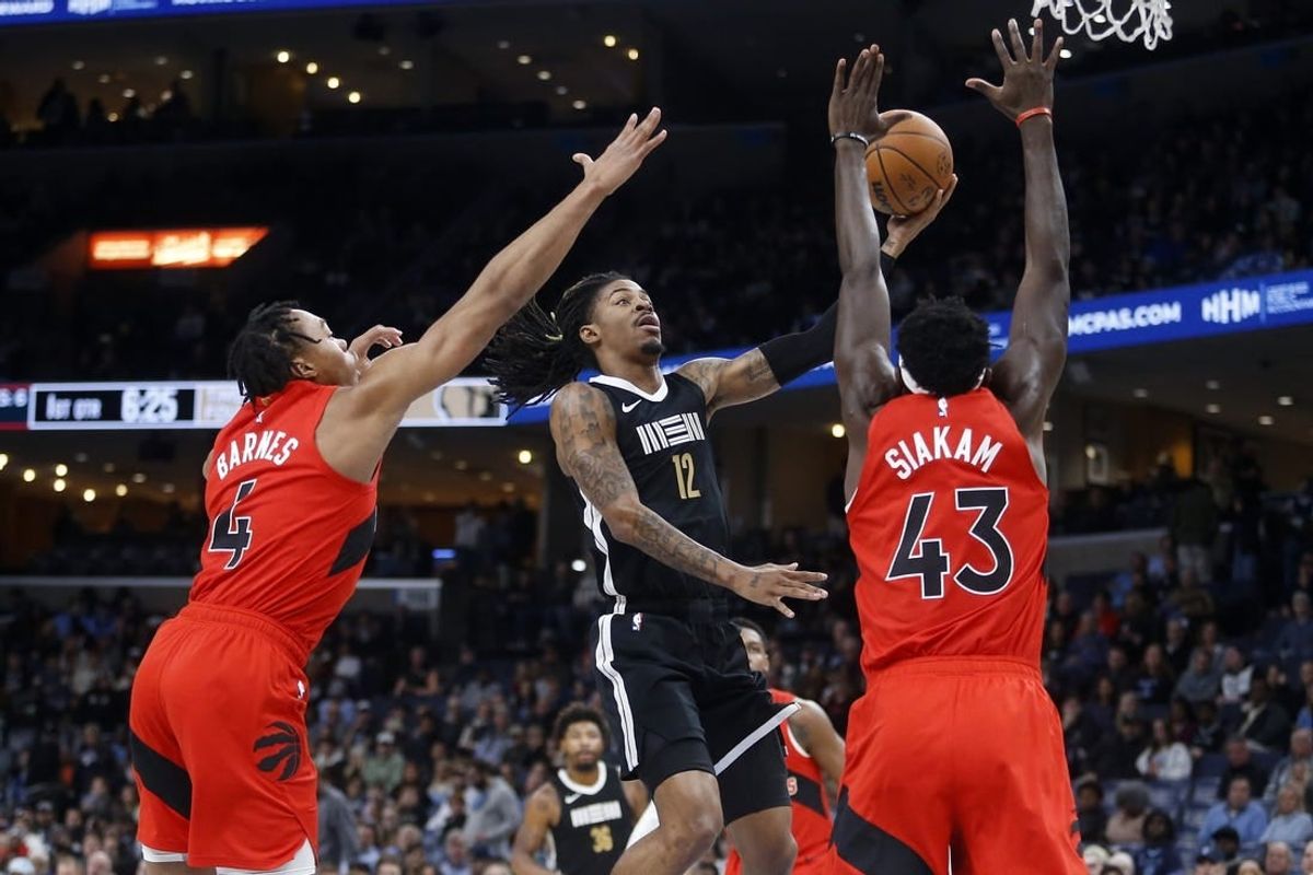 Jan 3, 2024; Memphis, Tennessee, USA; Memphis Grizzlies guard Ja Morant (12) drives to the basket between Toronto Raptors forward Scottie Barnes (4) and forward Pascal Siakam (43) during the first half at FedExForum.