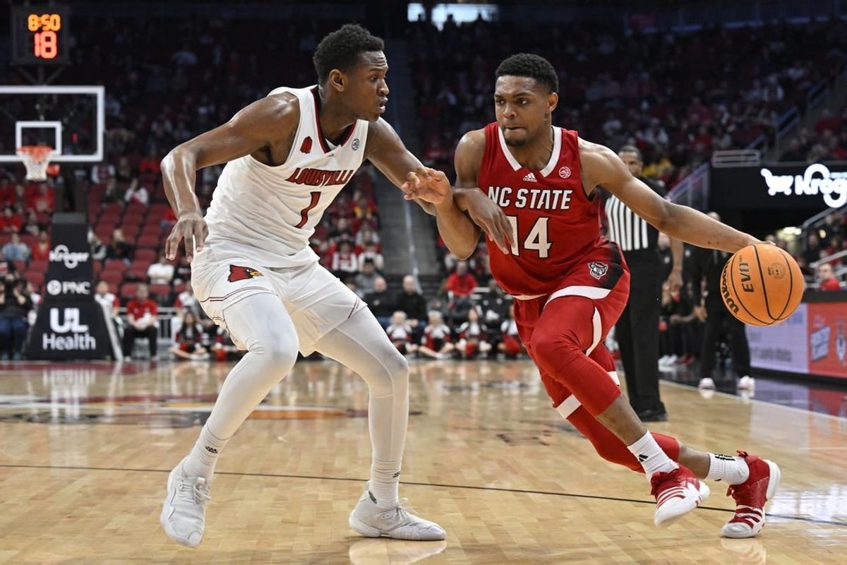 Jan 13, 2024; Louisville, Kentucky, USA;  North Carolina State Wolfpack guard Casey Morsell (14) dribbles the ball against Louisville Cardinals guard Curtis Williams (1) during the first half at KFC Yum! Center.