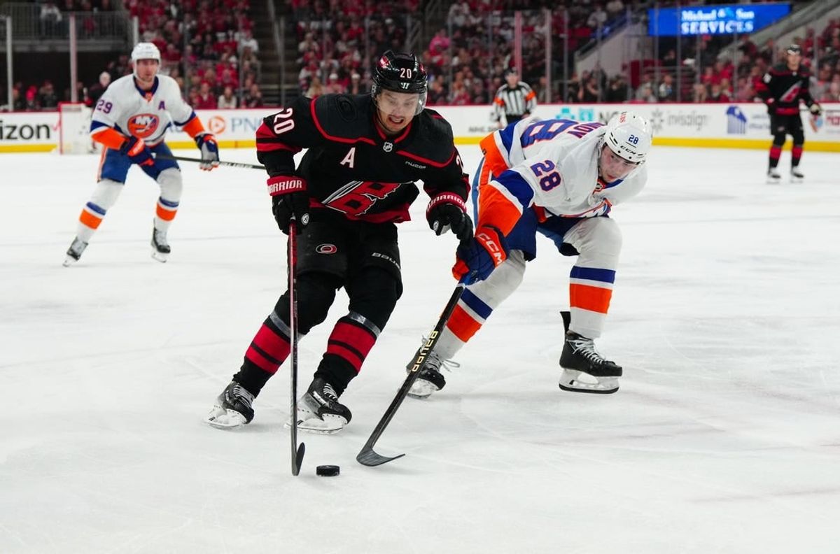 Apr 30, 2024; Raleigh, North Carolina, USA; Carolina Hurricanes center Sebastian Aho (20) skates with the puck past New York Islanders defenseman Alexander Romanov (28) during the first period in game five of the first round of the 2024 Stanley Cup Playoffs at PNC Arena.