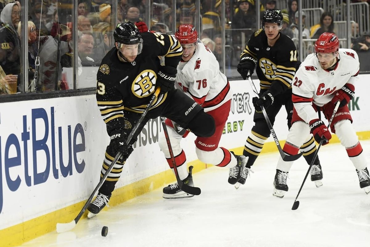 Jan 24, 2024; Boston, Massachusetts, USA;  Boston Bruins center Charlie Coyle (13) controls the puck while Carolina Hurricanes defenseman Brady Skjei (76) defends during the third period at TD Garden.