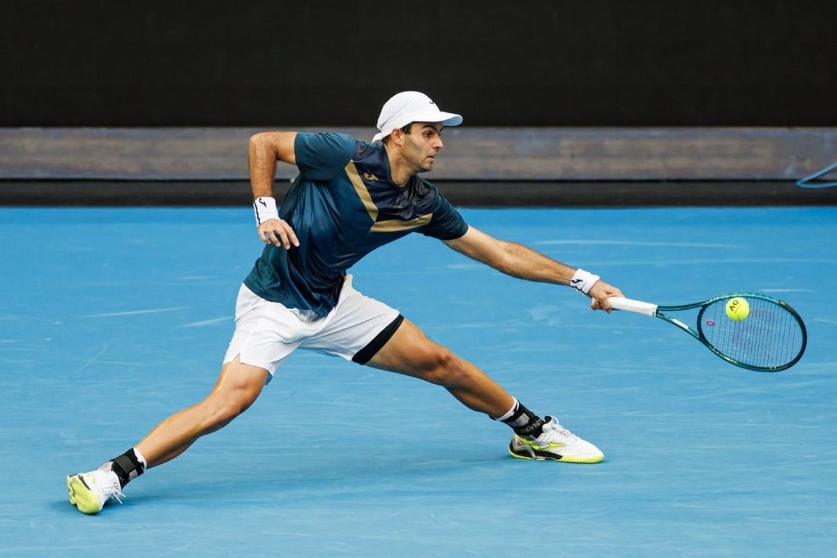 Jan 14, 2024; Melbourne, Victoria, Australia;  Facundo Diaz Acosta of Argentina hits a shot against Taylor Fritz of the United States in the first round of the men s singles.