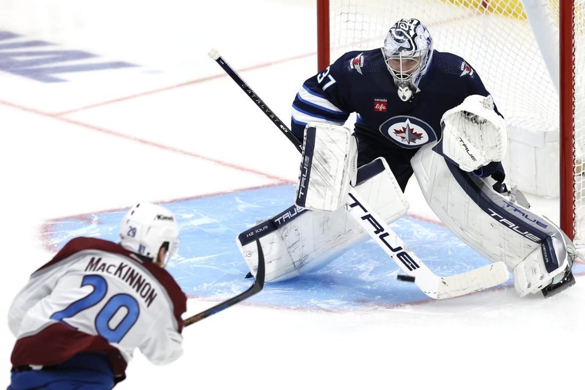 Apr 21, 2024; Winnipeg, Manitoba, CAN; Colorado Avalanche center Nathan MacKinnon (29) takes a shot on Winnipeg Jets goaltender Connor Hellebuyck (37) in the third period in game one of the first round of the 2024 Stanley Cup Playoffs at Canada Life Centre.