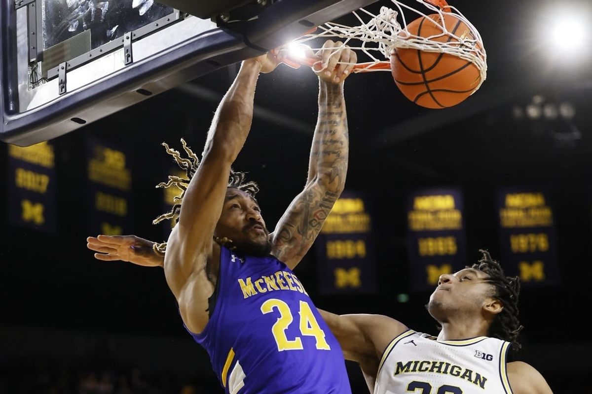 Dec 29, 2023; Ann Arbor, Michigan, USA;  McNeese State Cowboys forward Christian Shumate (24) dunks on Michigan Wolverines forward Tarris Reed Jr. (32) in the second half at Crisler Center.
