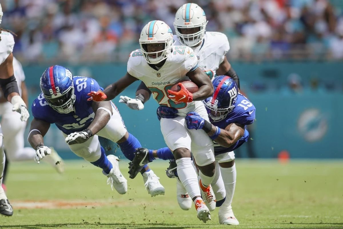Oct 8, 2023; Miami Gardens, Florida, USA; Miami Dolphins running back De'Von Achane (28) runs with the football ahead of New York Giants safety Isaiah Simmons (19) and defensive tackle Rakeem Nunez-Roches (93) during the second quarter at Hard Rock Stadium.