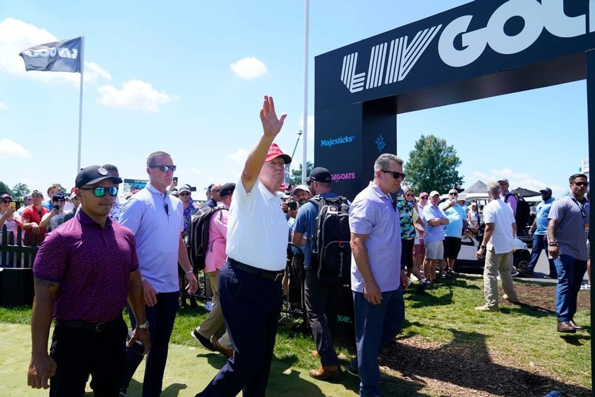 Former President Donald Trump waves to the crowd as he exits the putting green with his aide Walt Nauta, left, during the final round of the LIV Golf Bedminster golf tournament at Trump National Bedminster on Sunday, Aug. 13, 2023.